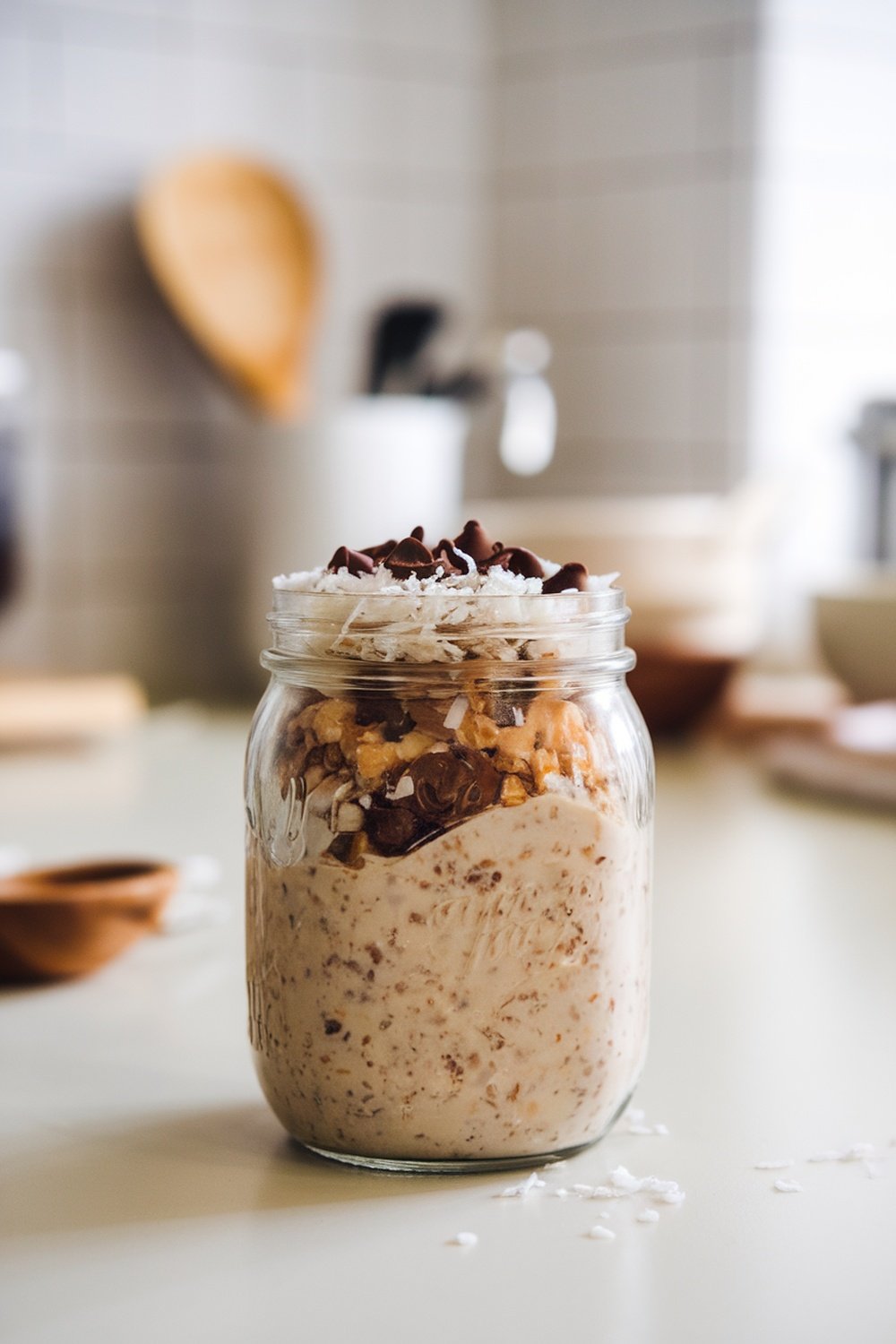 A jar of chocolate coconut overnight oats topped with shredded coconut and chocolate chips.