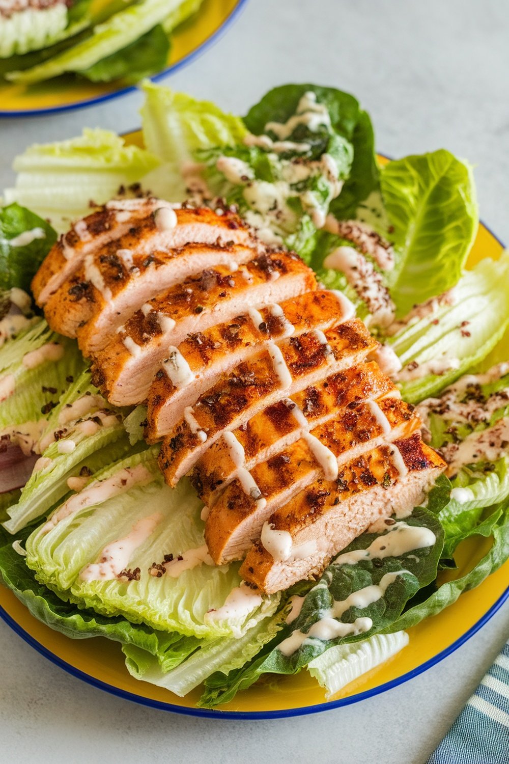 A delicious Grilled Chicken Caesar Salad with sliced grilled chicken on romaine lettuce, drizzled with Caesar dressing.